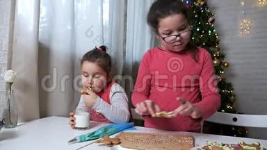 圣诞树背景上的两个<strong>小</strong>女孩<strong>小姐姐</strong>.. 一个女孩喝牛奶和姜饼饼干